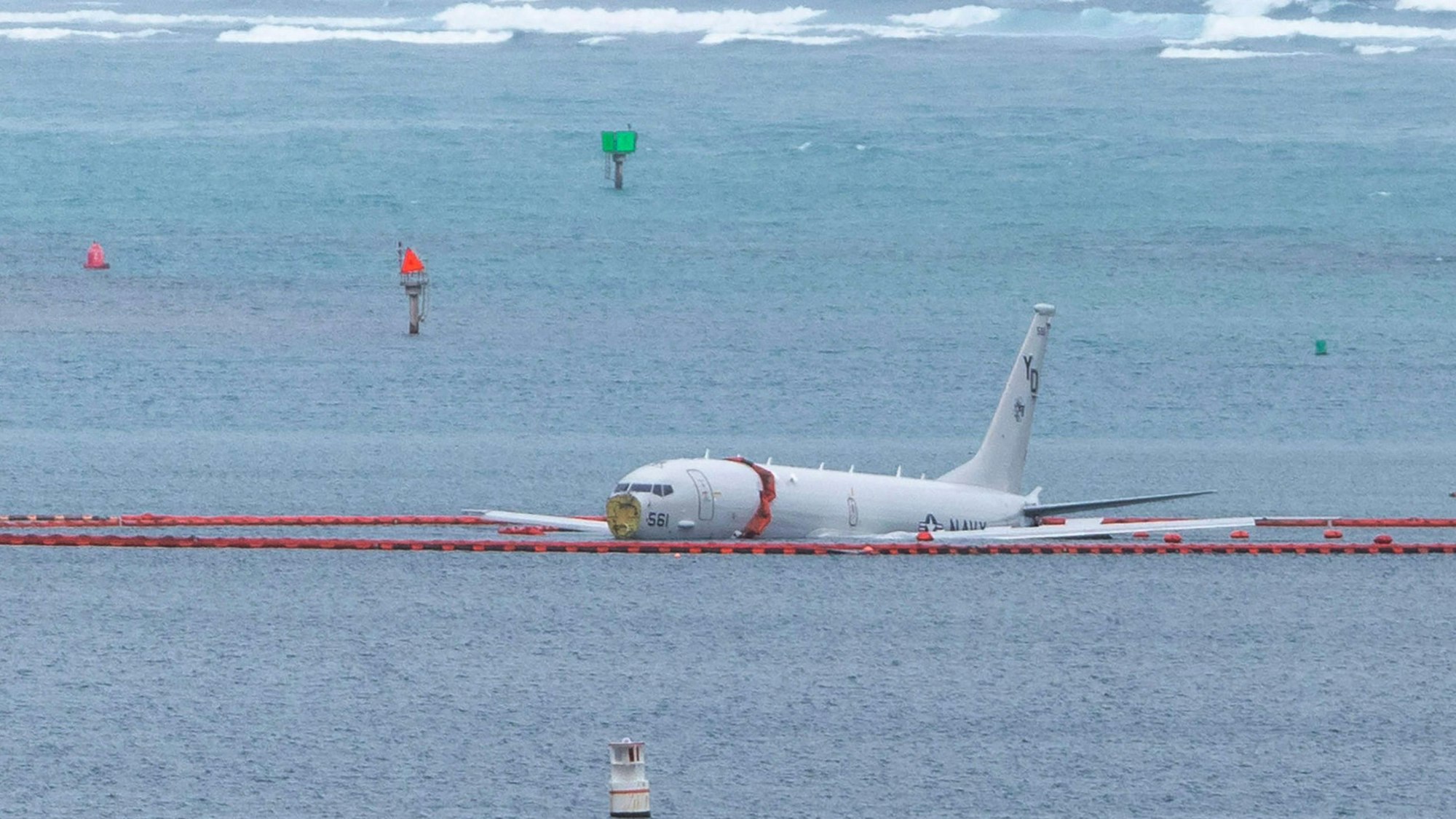 A military aircraft lies in the shallow waters of Kaneohe Bay after skidding off the end of the runway at Marine Corps Hawaii in Kaneohe on November 20, 2023. The aircraft is a Boeing P8 Poseidon, described as a military surveillance and patrol aircraft. Authorities confirmed the nine people on board made it to shore uninjured. The crew was conducting routine training at the time, according to military officials. (Photo by Eugene Tanner / AFP)