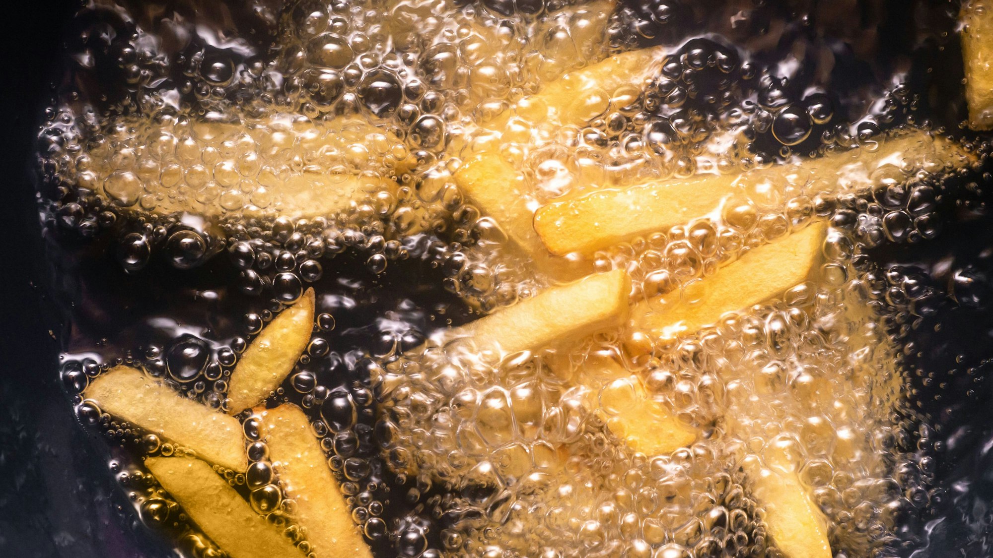 Pommes frites werden in heissem Öl frittiert *** French fries are deep fried in hot oil 1028901606