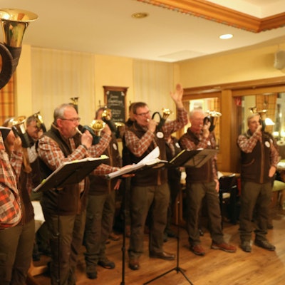 Ein Gruppe von Jagdhornbläsern folgt dem Signal ihres Leiters.
