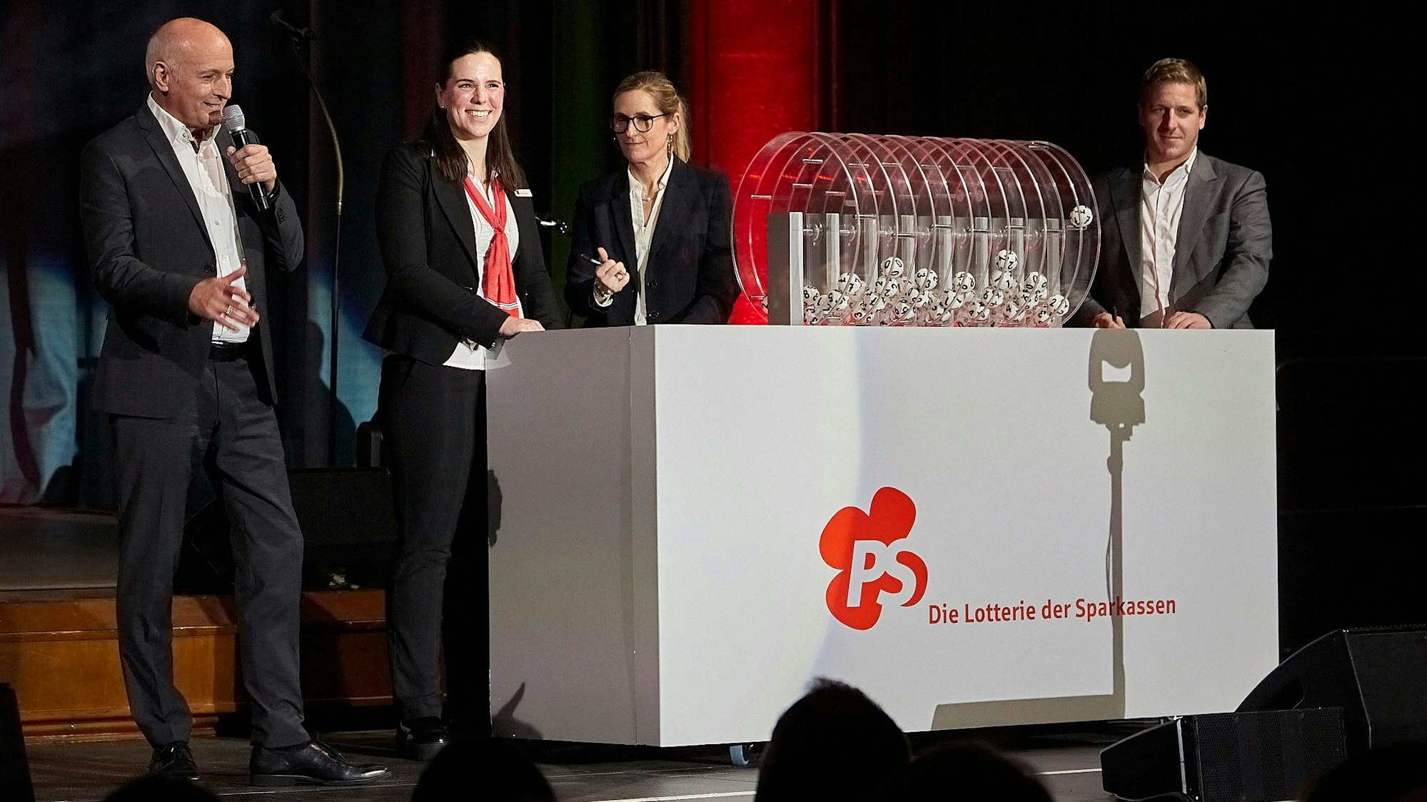 In einem Drehbehälter rollen die Loskugeln unter den Blicken der für die Ziehung Verantwortlichen.