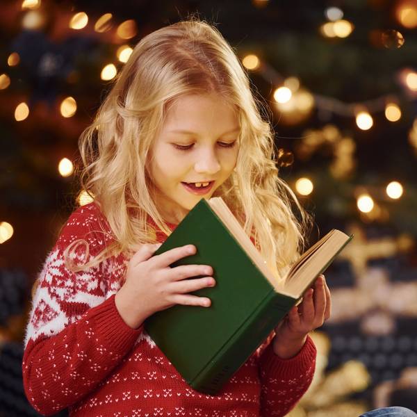Symbolbild: Mädchen liest ein Buch vor weihnachtlicher Beleuchtung