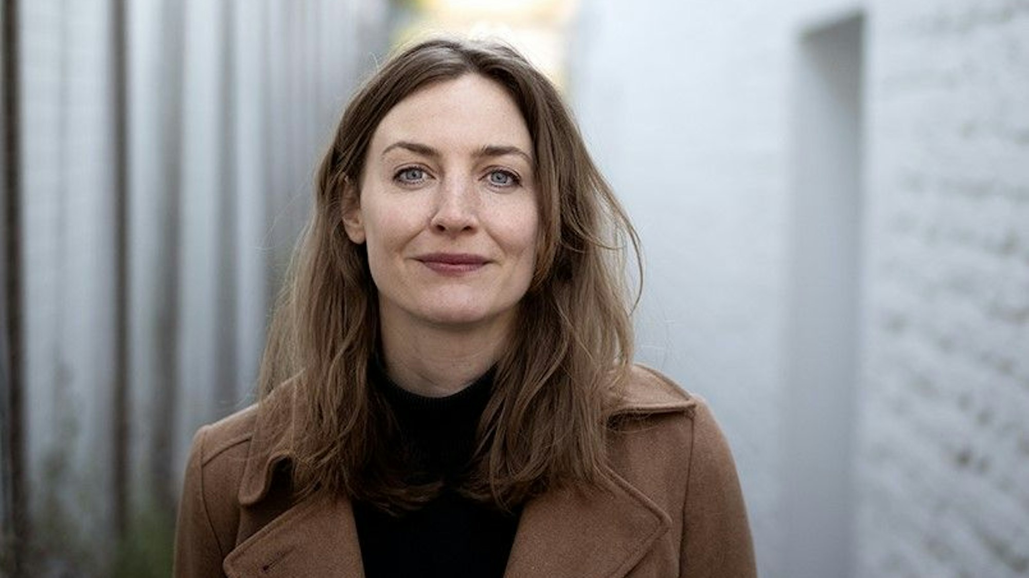 Tatort-Kommissarin Ines Westernströer  trägt einen braunen Mantel und guckt in die Kamera