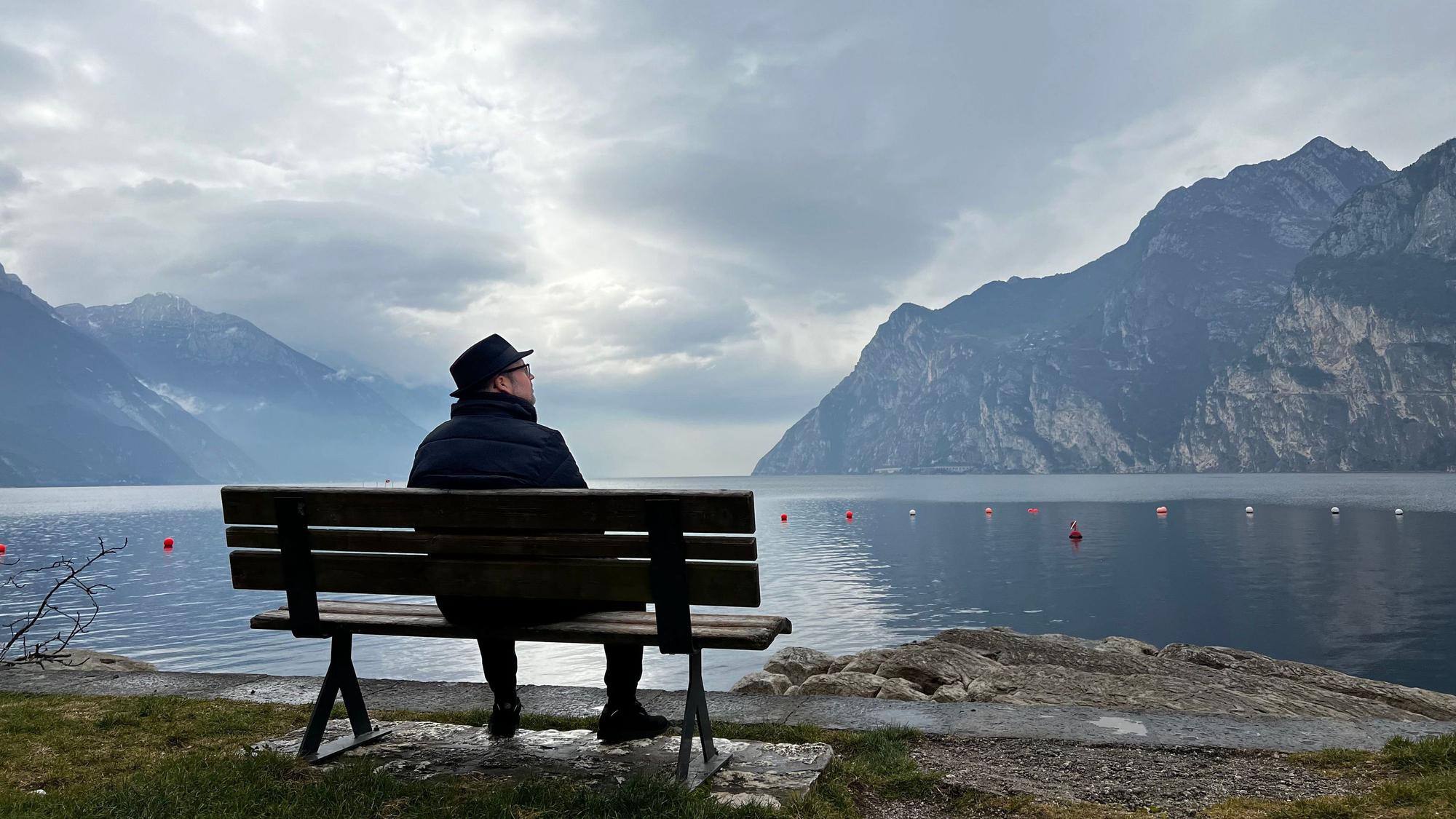 Björn Heuser sitzt auf einer Bank am Gardasee
