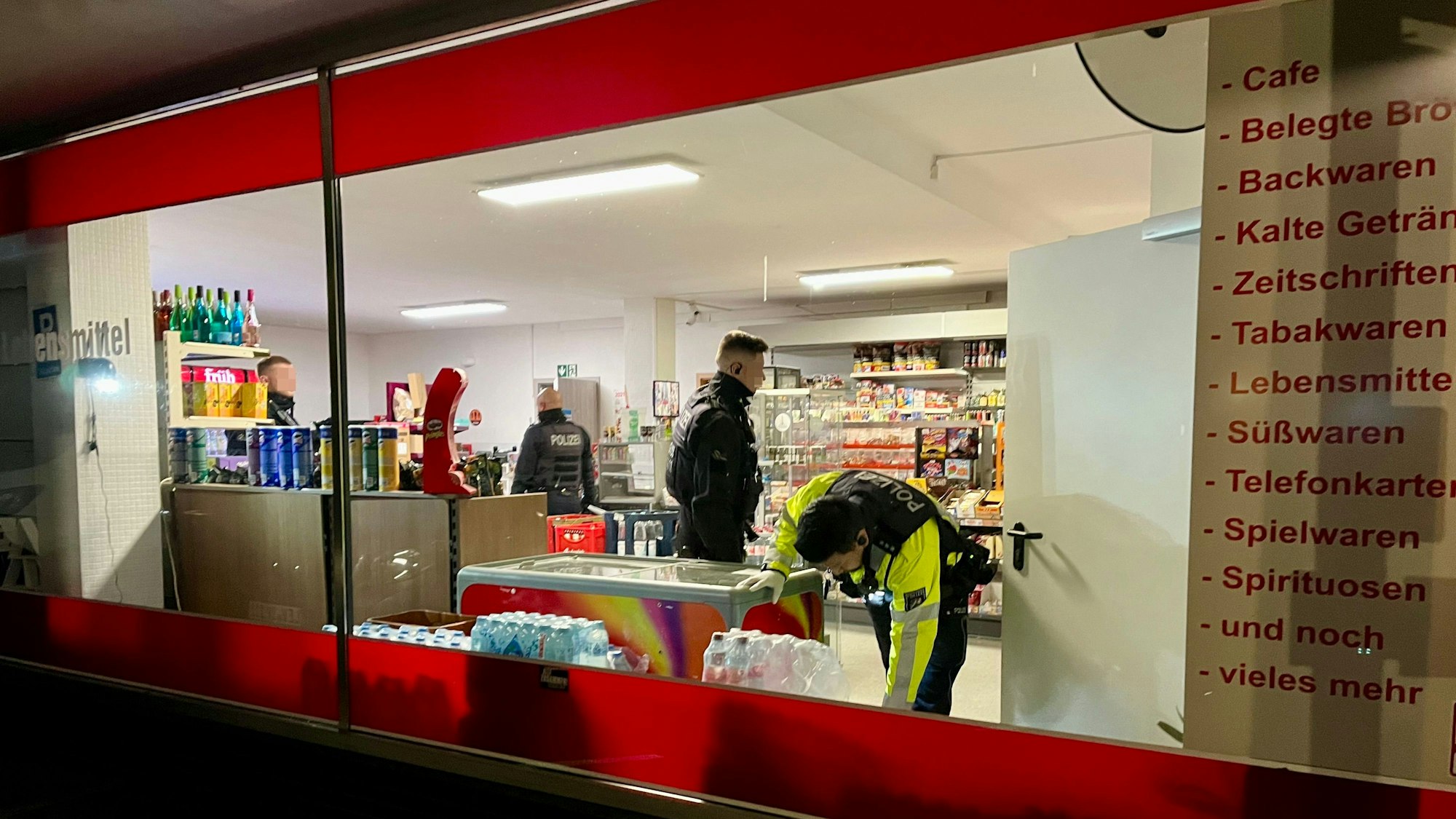 Mitarbeitende von Polizei und Ordnungsamt durchsuchen einen Kiosk in Rheindorf.