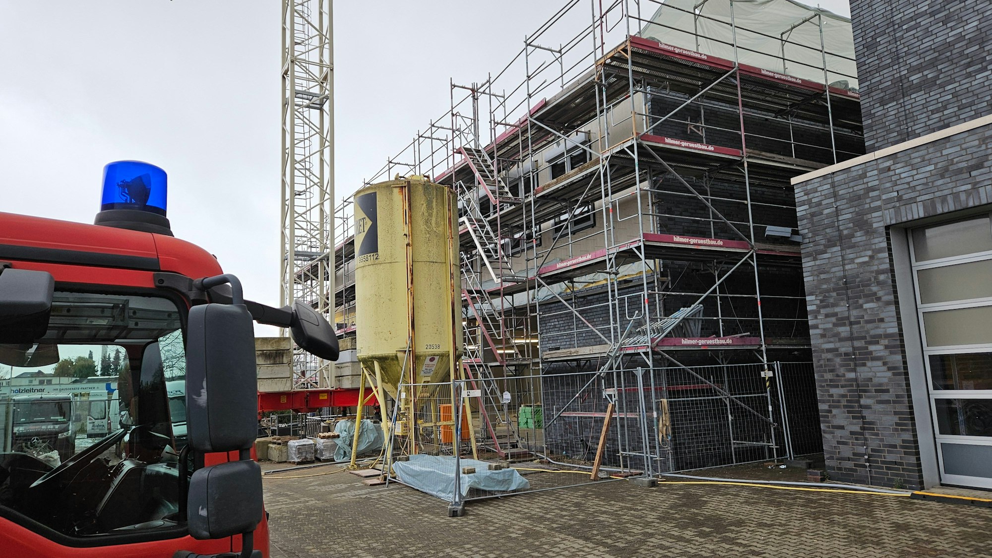 Ein Feuerwehrwagen steht vor einer Baustelle, ein Gebäude ist eingerüstet.