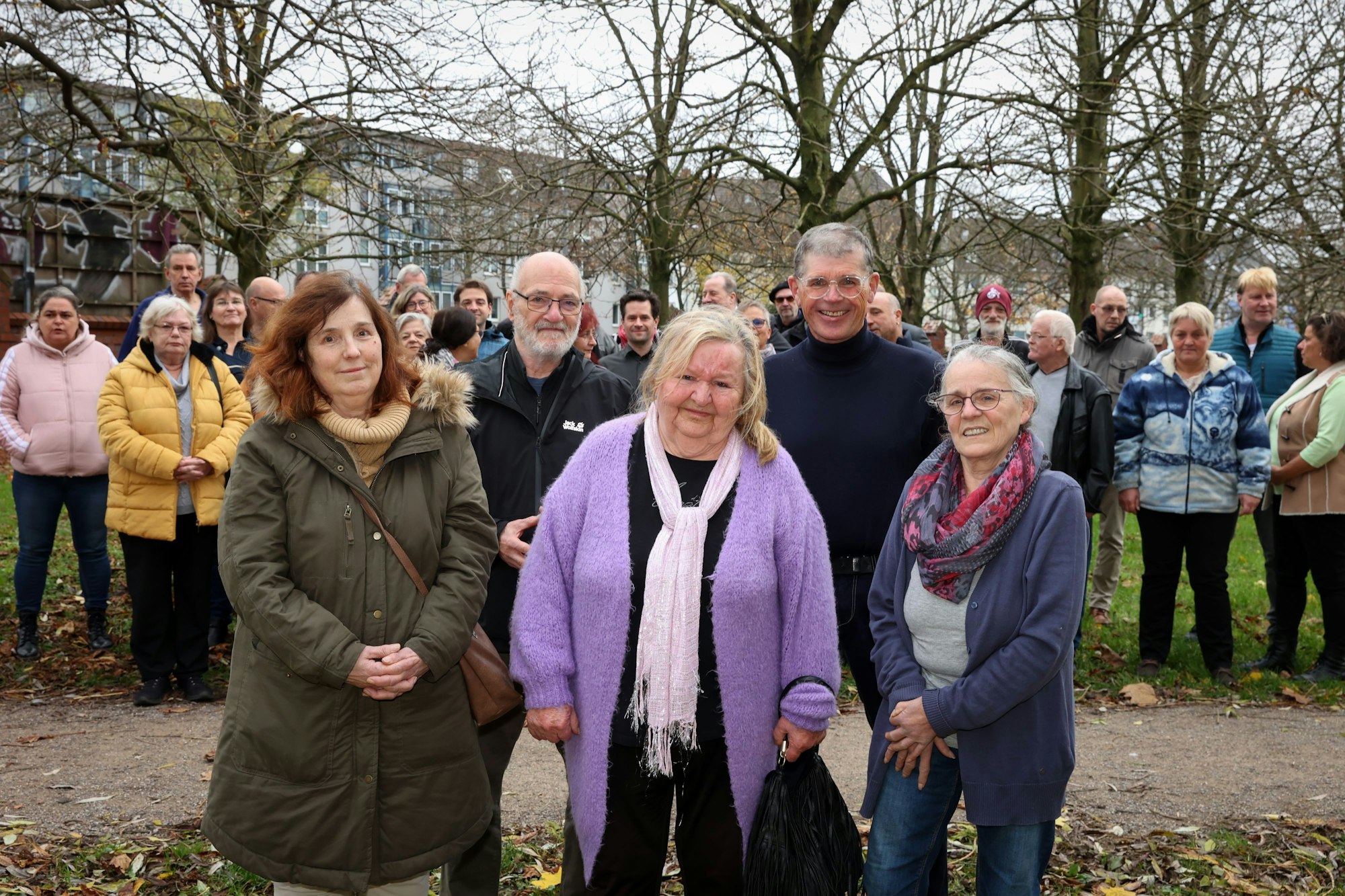 Viele Menschen stehen gemeinsam in einem Park.