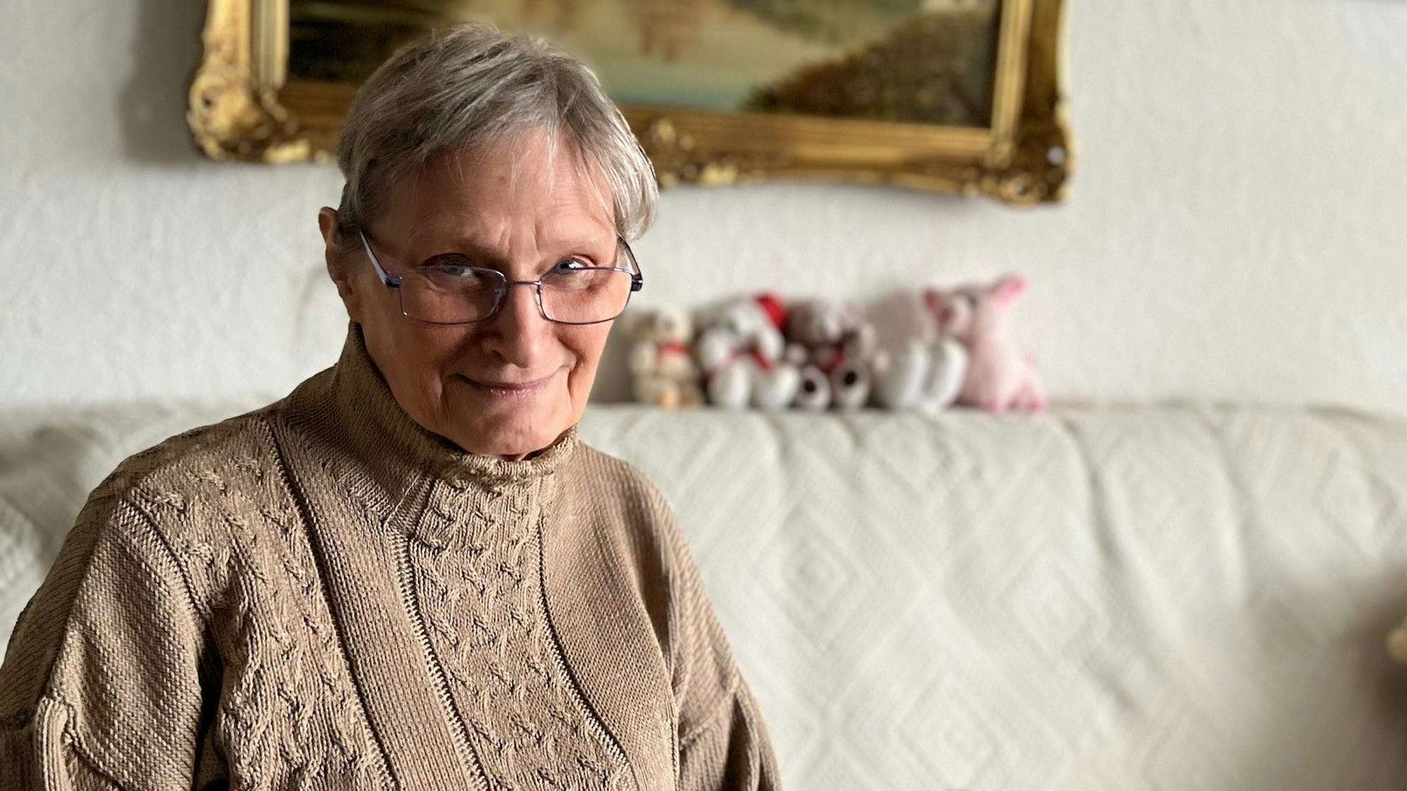 Monika Stampe sitzt auf dem Sofa in ihrem Wohnzimmer.