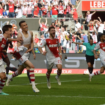 Jubelnd laufen mehrere Spieler des 1. FC Köln über das Spielfeld. Einer hat sich das Trikot ausgezogen.