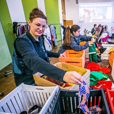 Eine Frau sortiert Karnevalskostüme in unterschiedliche Kisten.