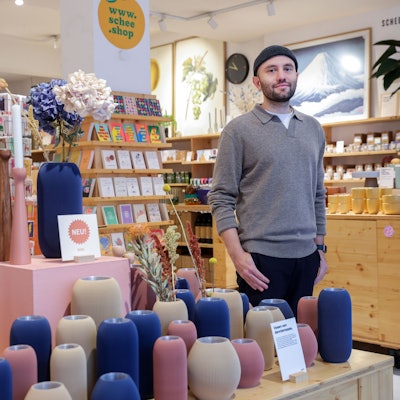 Ein Mann steht in einem Dekoladen mit vielen Vasen und Postkarten.
