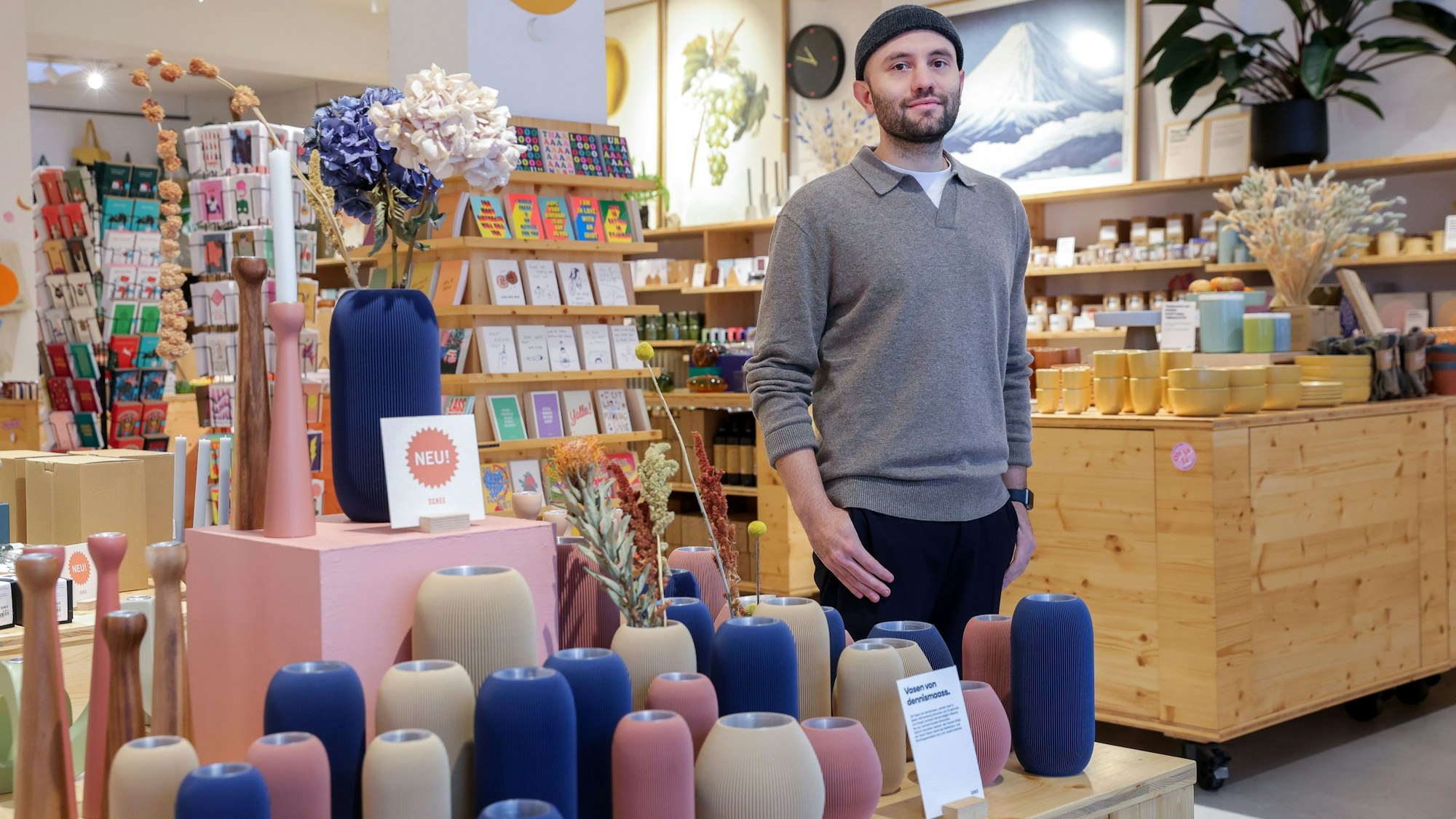 Ein Mann steht in einem Dekoladen mit vielen Vasen und Postkarten.