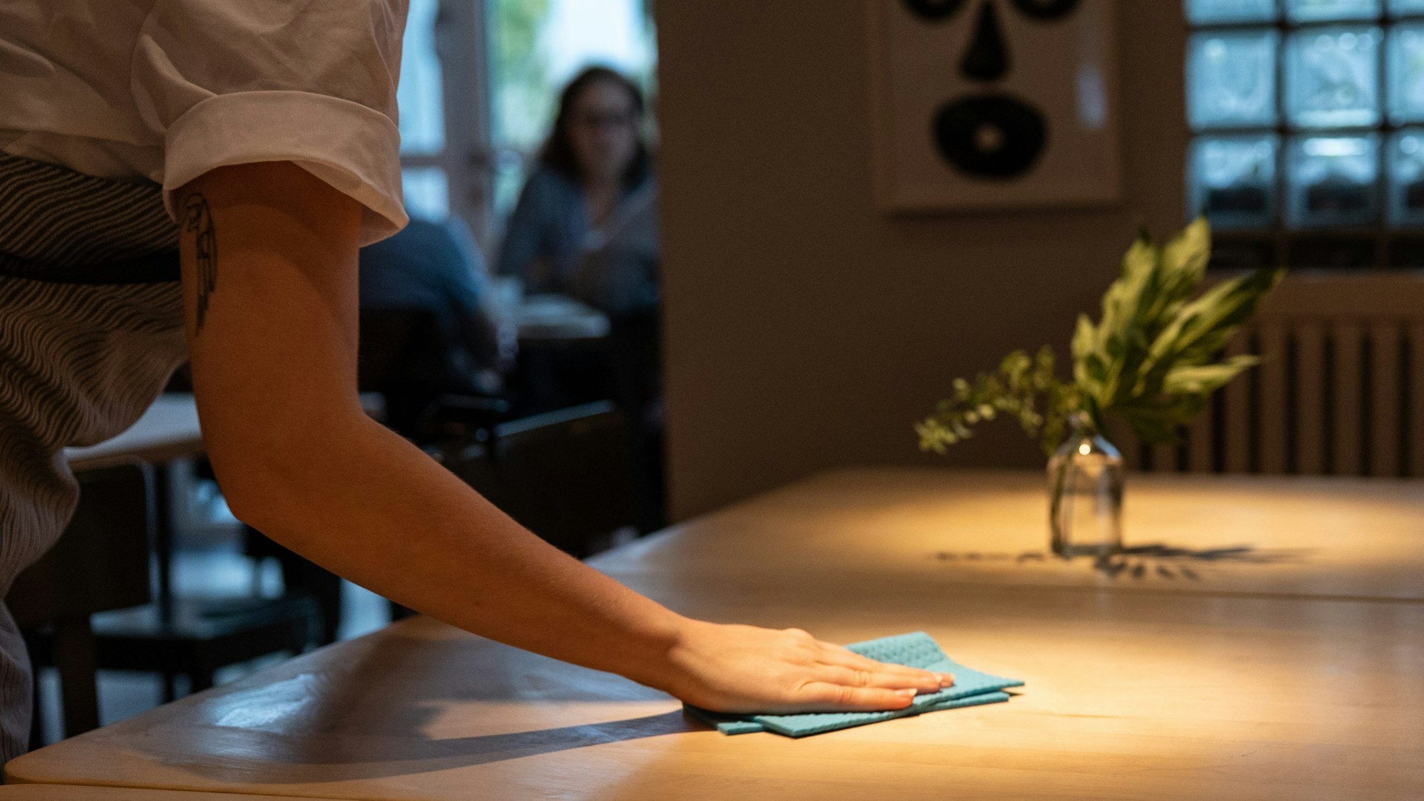 Eine Bedienung wischt einen Tisch in einem Restaurant ab.