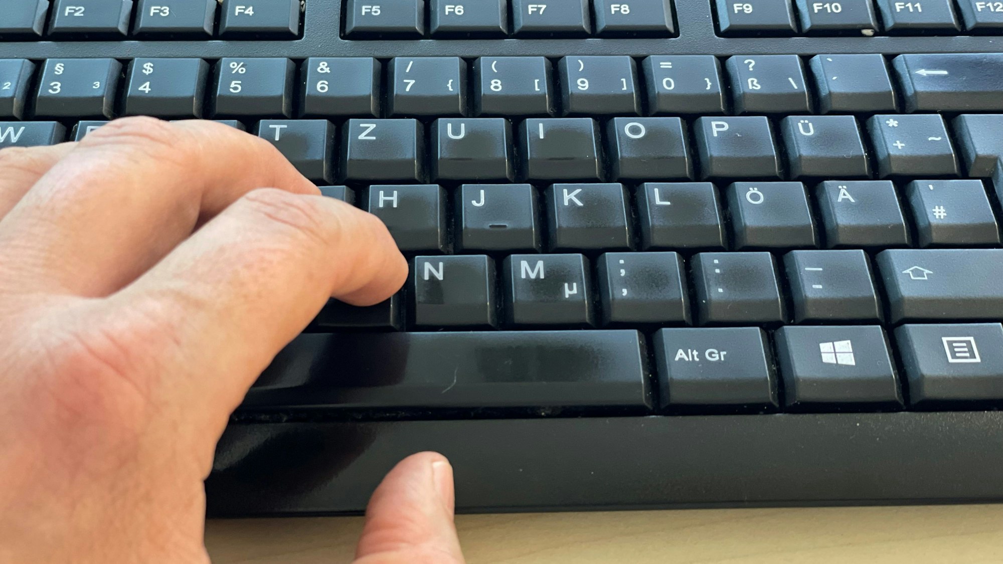 Das Bild zeigt eine Computertastatur und die Finger einer linken Hand.