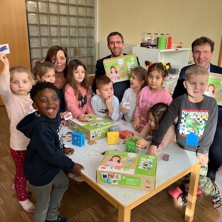 Drei Erwachsene und viele Kinder mit dem neuen Spiel.