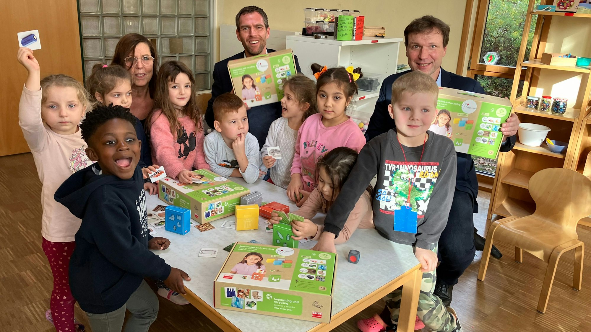 Drei Erwachsene und viele Kinder mit dem neuen Spiel.