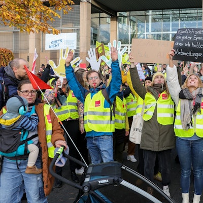 Streikende in Warnwesten halten Plakate hoch.