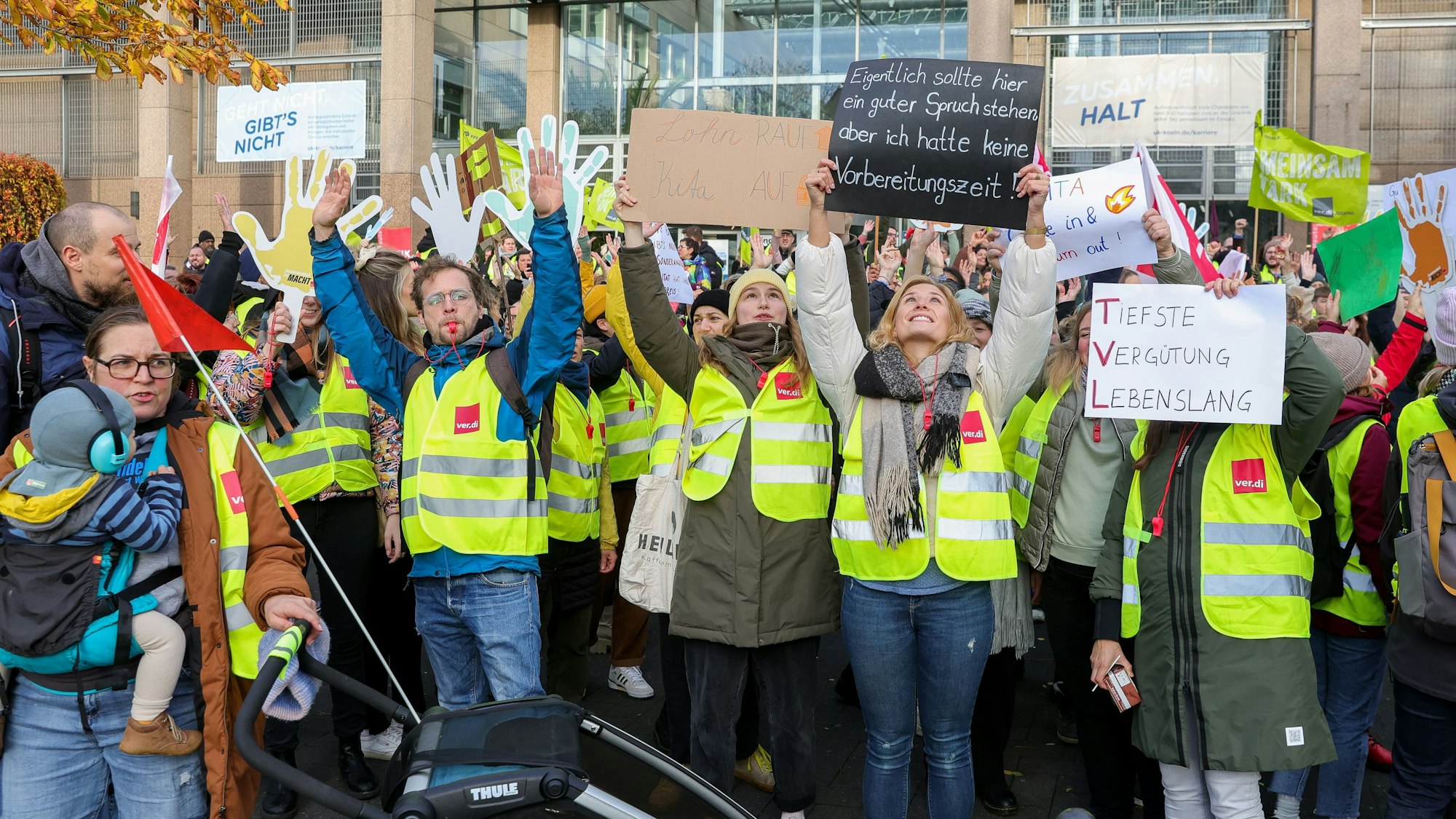 Streikende in Warnwesten halten Plakate hoch.