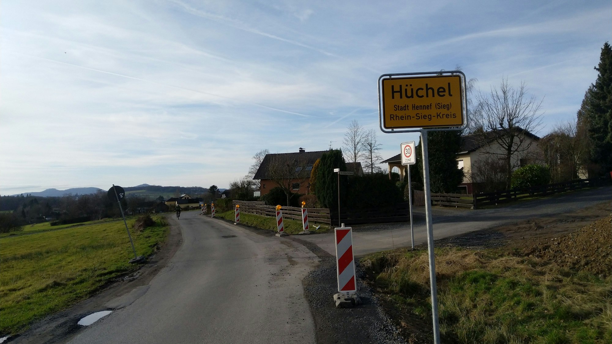 Ein Ortsschild steht an einer ländlichen Straße.