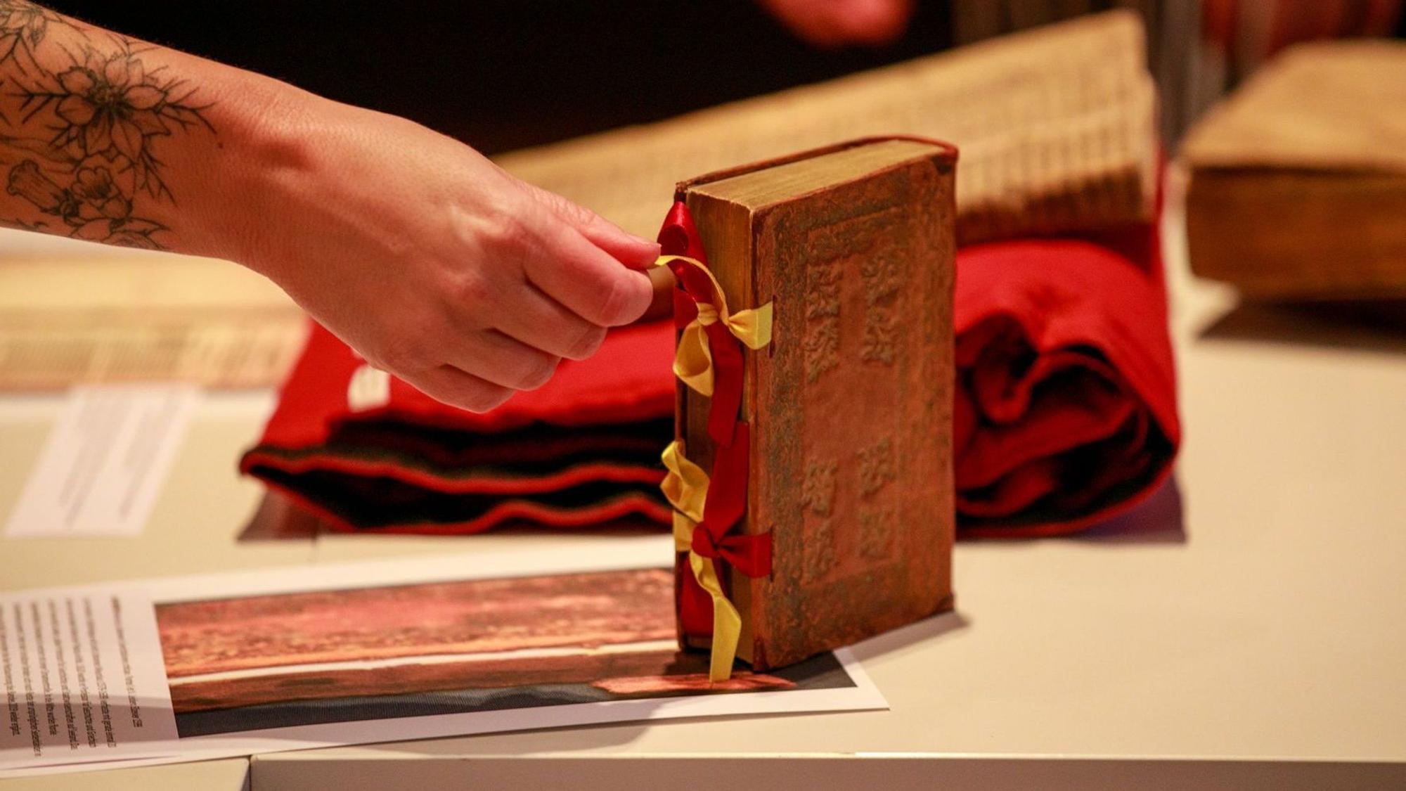Im Showroom beim Festakt zur Rettung der Wallraf-Bibliothek sieh man ein restauriertes Buch, eine Hand hält eine Schleife, die es verschließt.