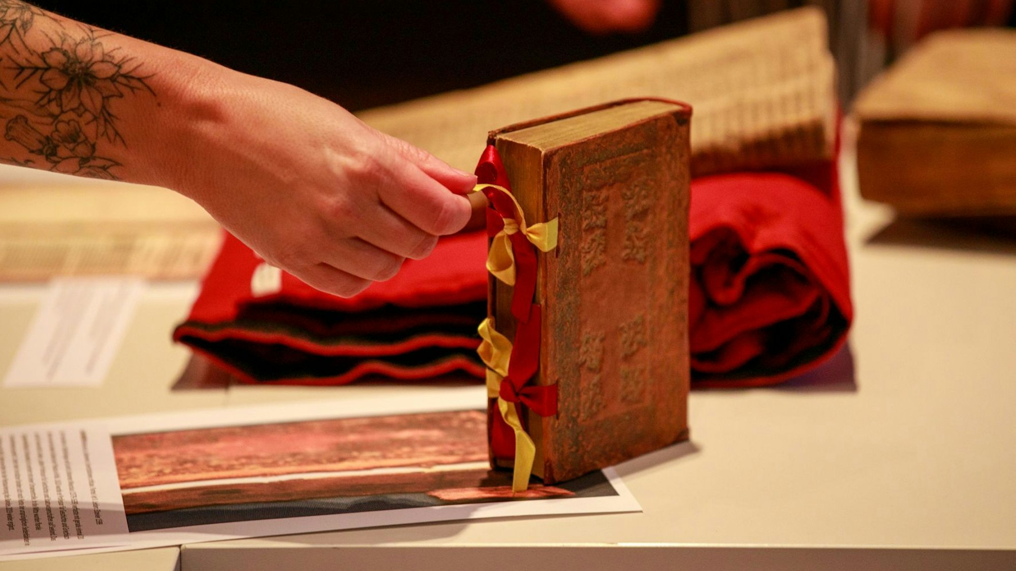 Im Showroom beim Festakt zur Rettung der Wallraf-Bibliothek sieh man ein restauriertes Buch, eine Hand hält eine Schleife, die es verschließt.