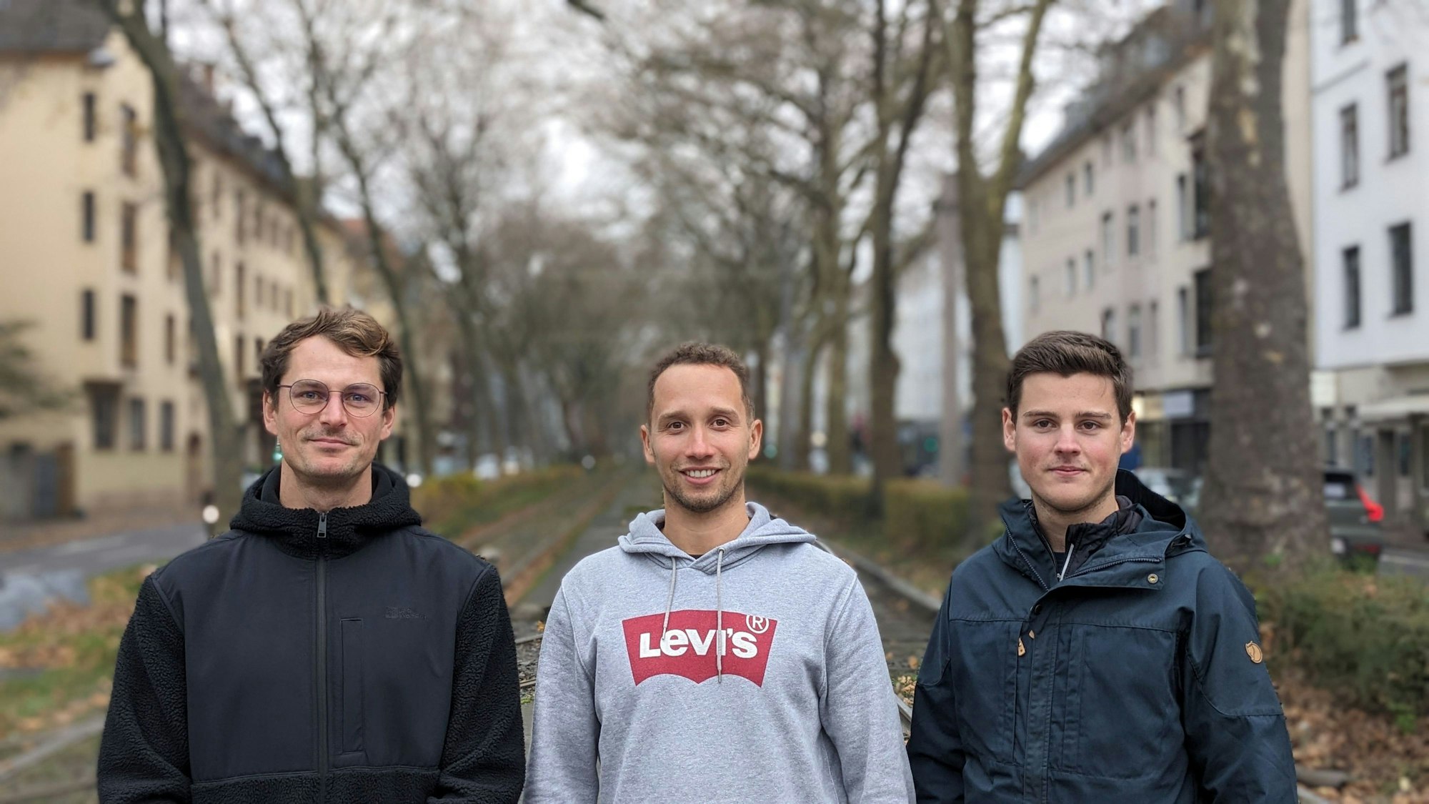 Max Krumm, Geronimo Pfeffer und Michel Sayn stehen auf einer Straße in Köln.