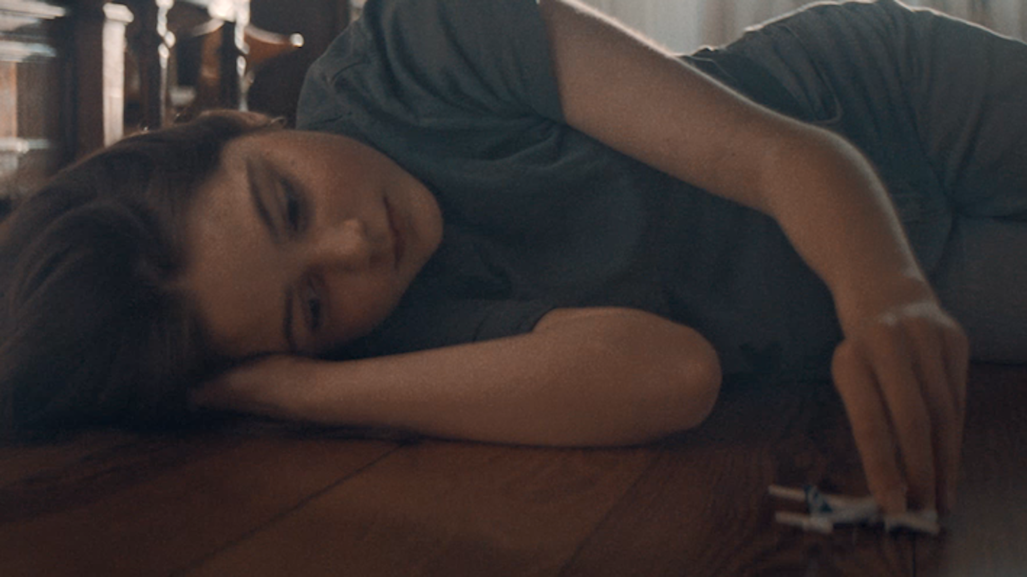 Ein Mädchen liegt auf dem Holzboden und hat ein kleines Flugzeug in der Hand, sie träumt davon, Pilotin zu werden.