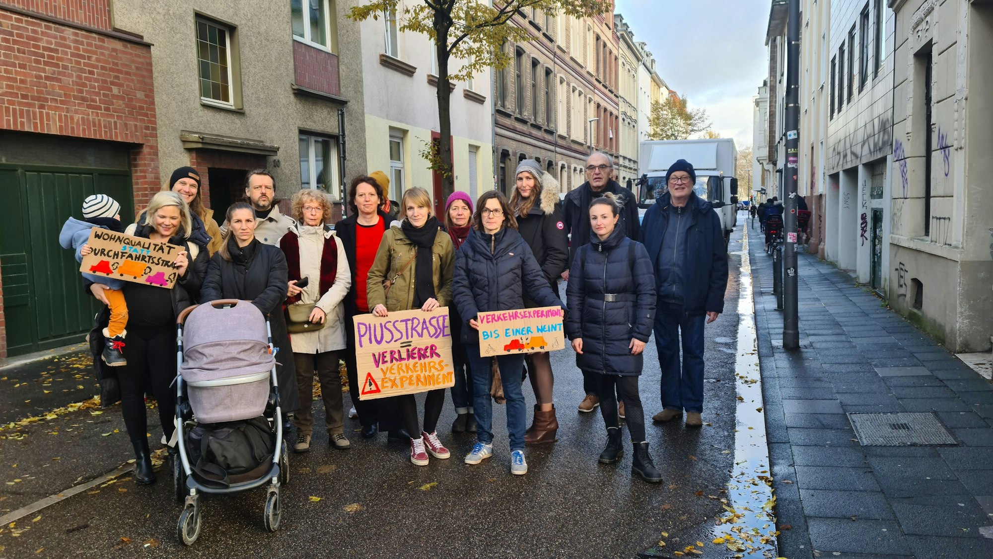 Eine Menschengruppe steht auf der Fahrbahn, einige alten Pappschilder hoch.