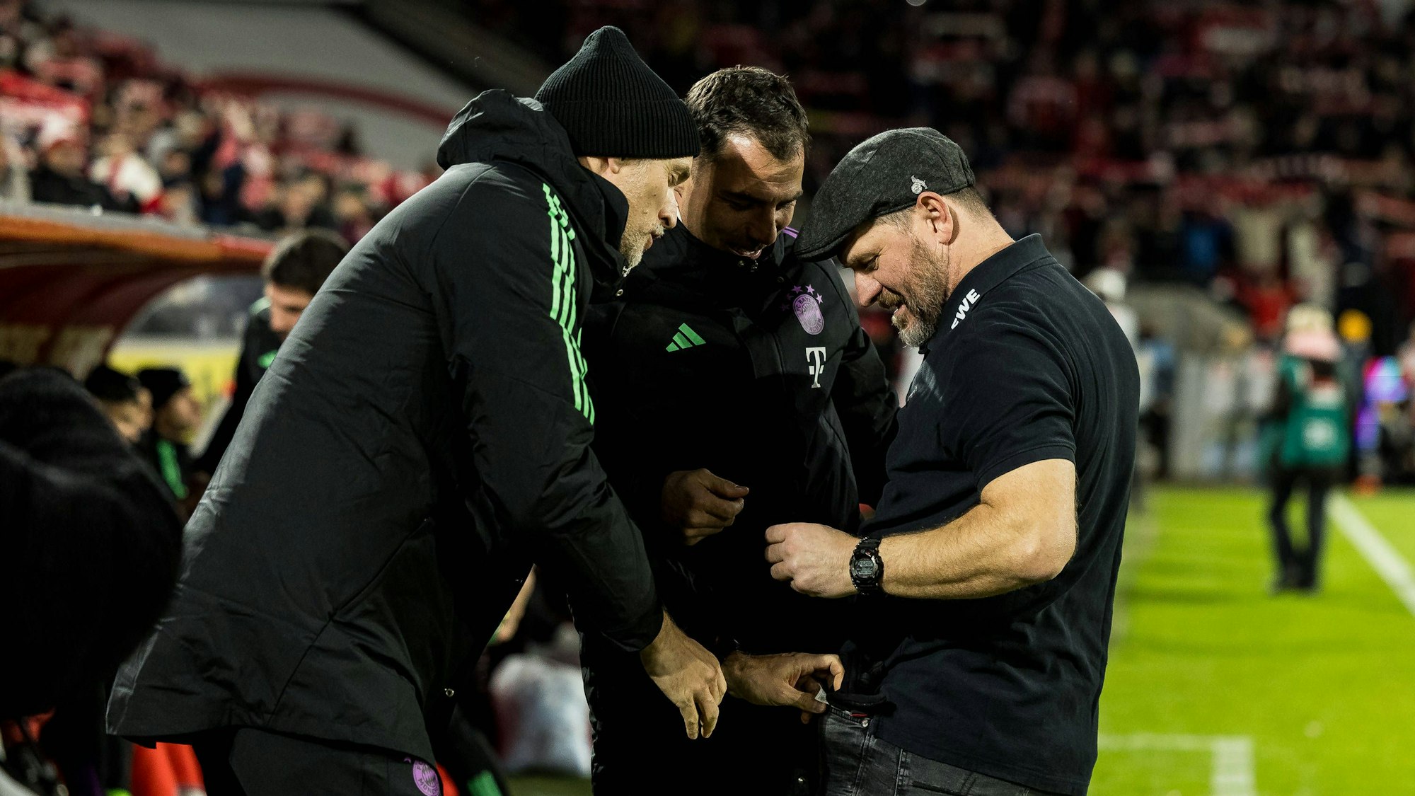 Bayern-Trainer Thomas Tuchel und Steffen Baumgart bei der Geschenkübergabe vor der Bayern-Bank.