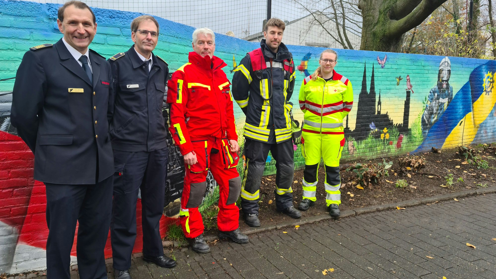 Fünf Leute stehen an einer Wand.