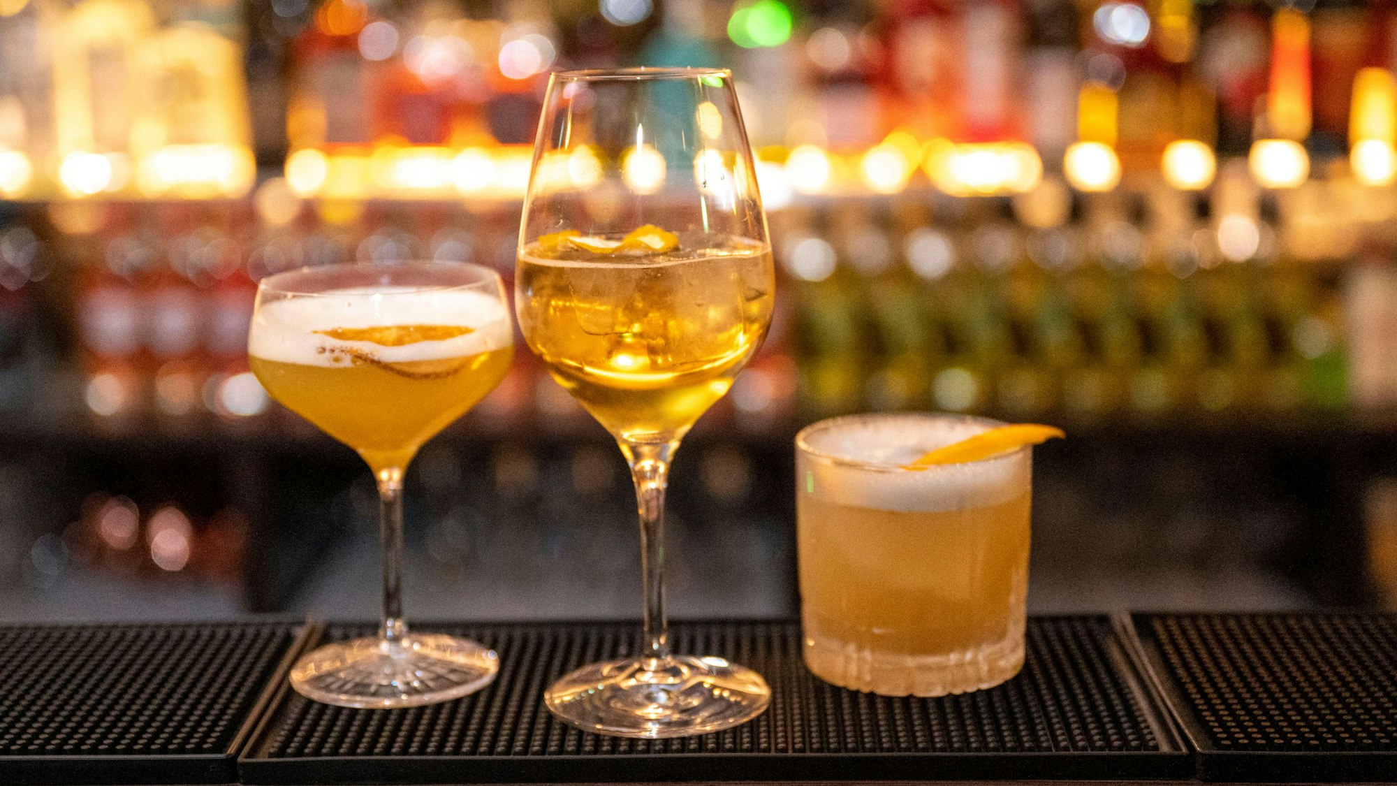 Drei Getränke stehen auf dem Tresen einer Bar.