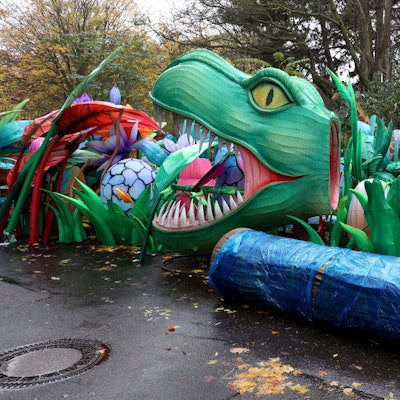 An einem Weg auf dem Hinterhof des Kölner Zoos türmen sich Einzelteile der Lichtskulpturen, darunter ein Dinosaurierkopf, Insekten und Pflanzen.