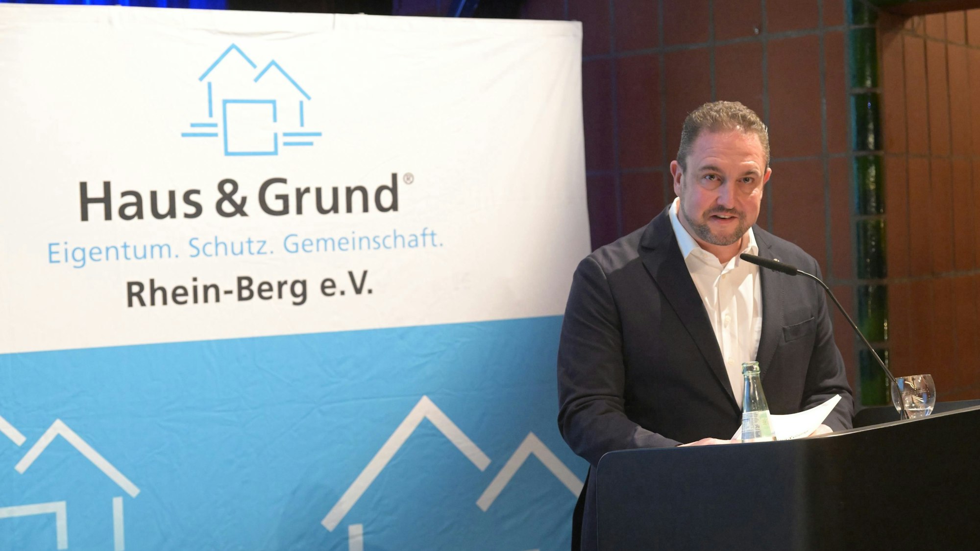 Sebastian Feik steht am Rednerpult von Haus & Grund Rhein-Berg.
