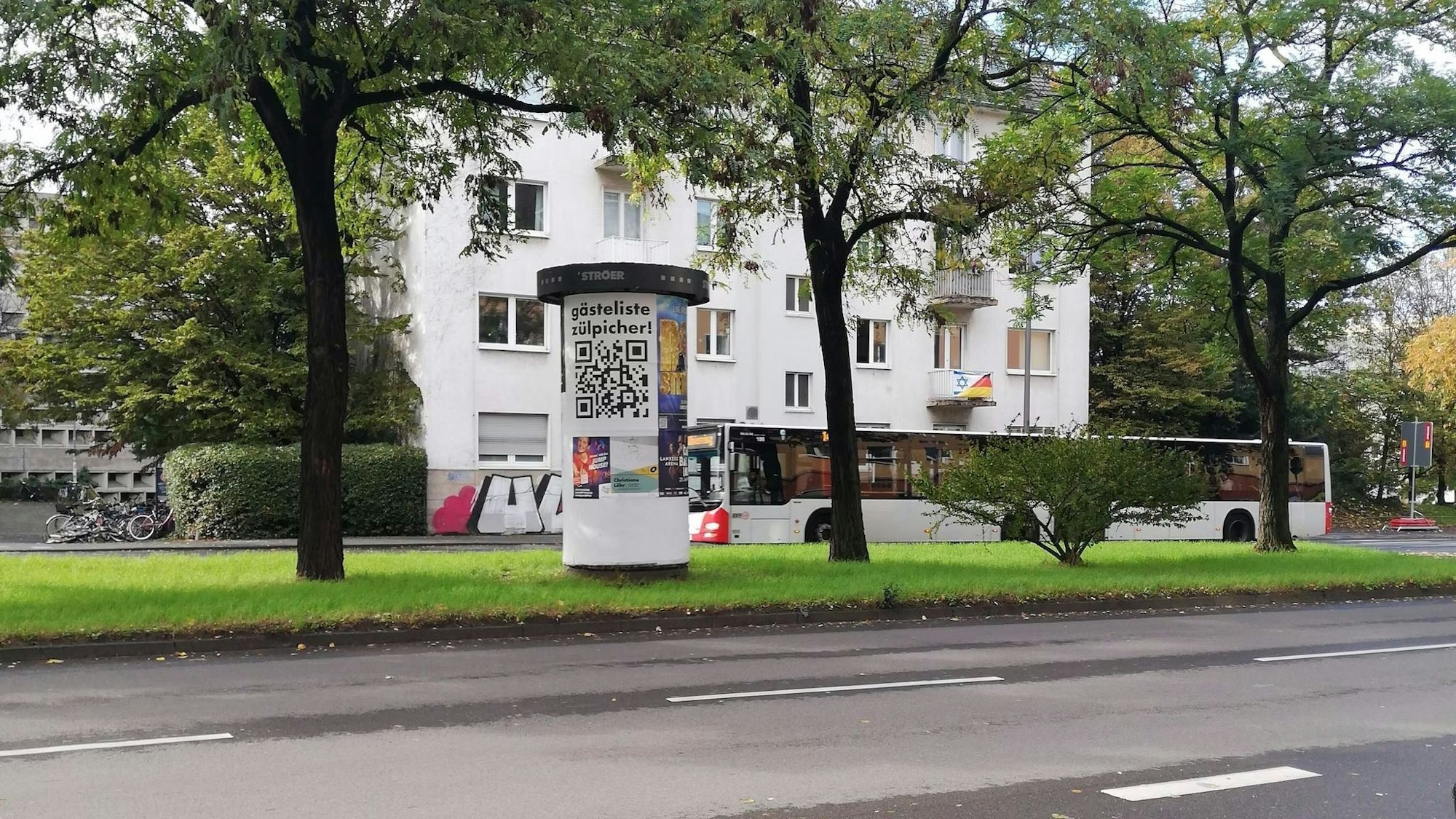 Auf einer Litfaßsäule hängt ein Plakat mit der Aufschrift „Gästeliste Zülpicher“, darunter ist ein großer QR-Code gedruckt.