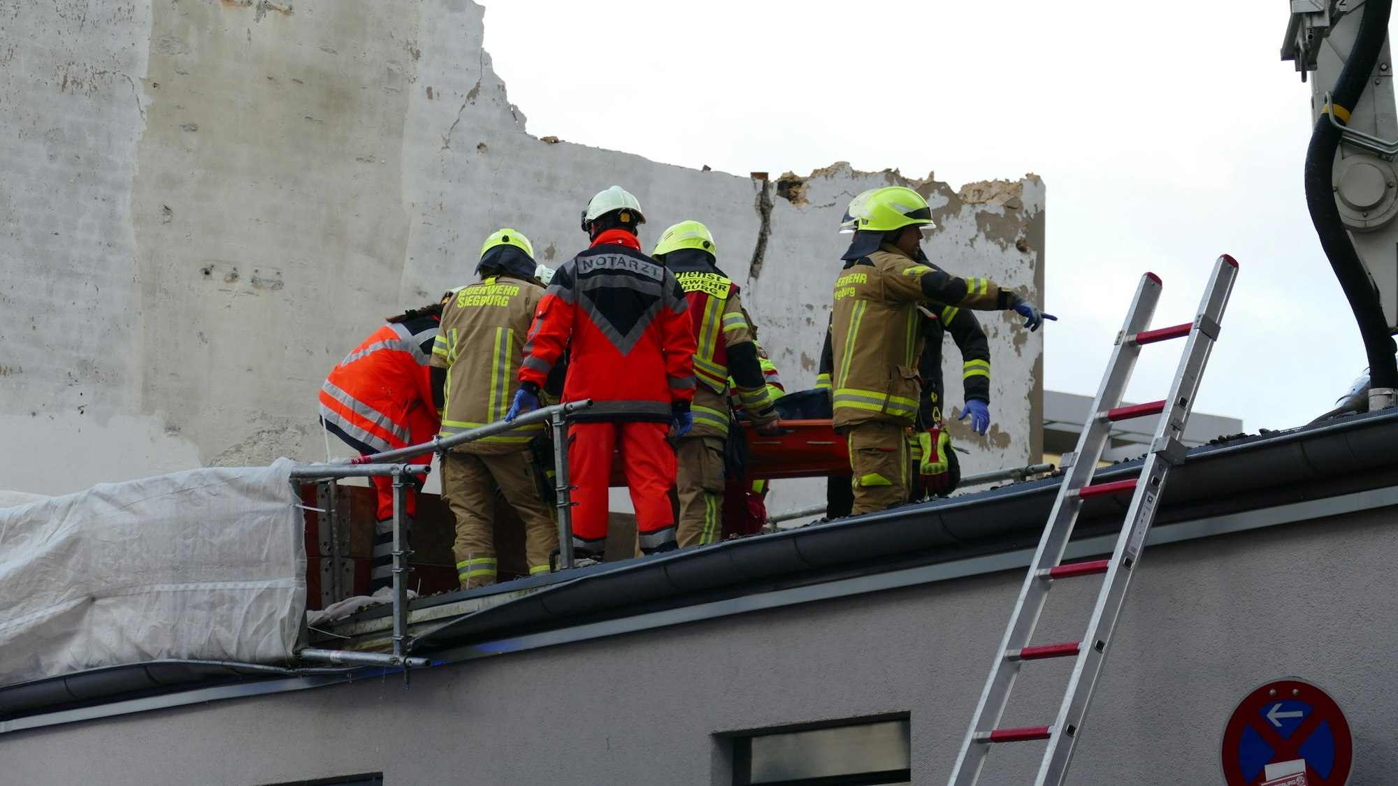 Rettungskräfte stehen auf einem Dach.