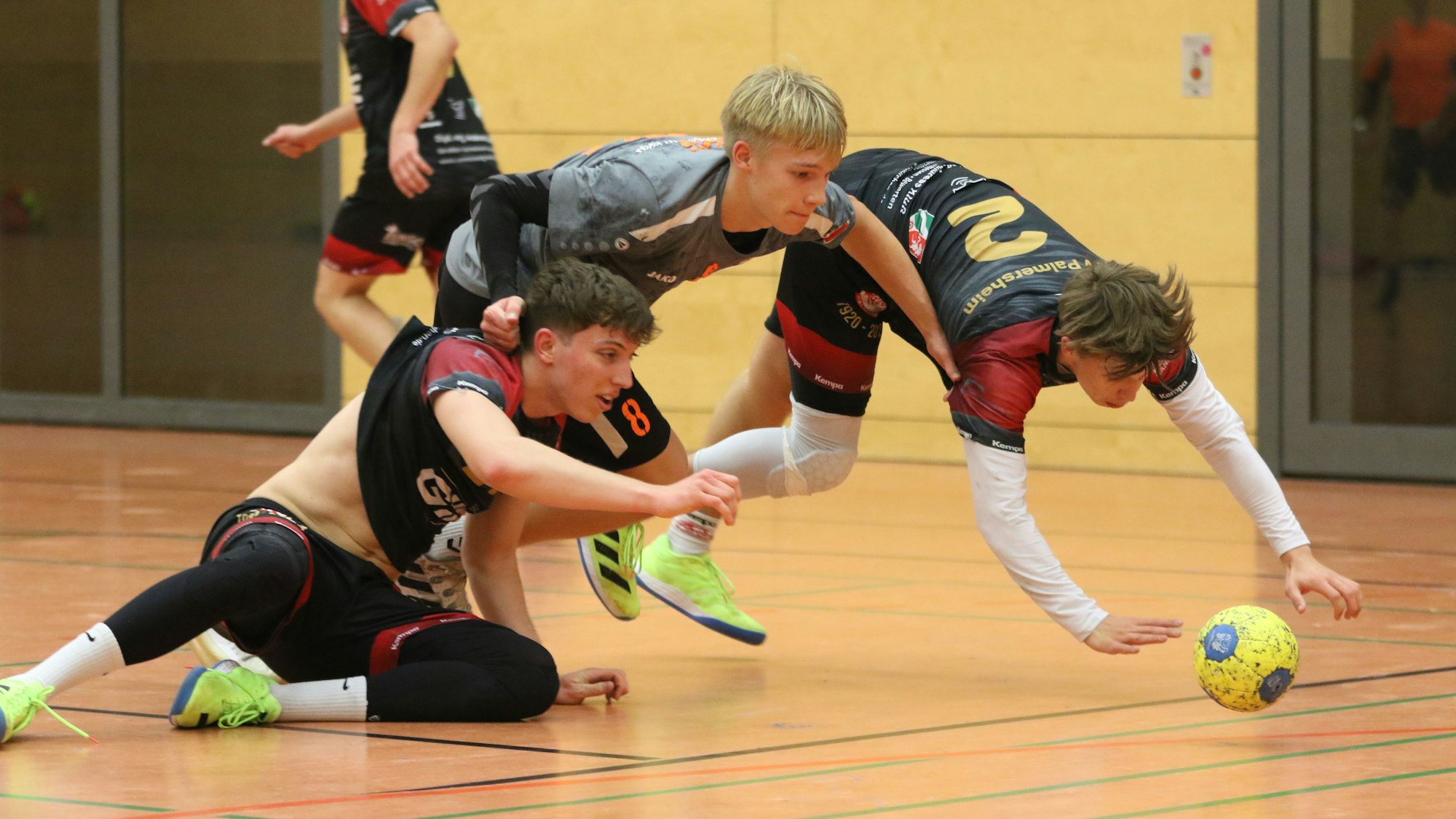 Ein Palmersheimer sitzt auf dem Boden, einer anderer stürzt dem Ball hinterher, zwischen den beiden steht noch halb ein Gegenspieler.