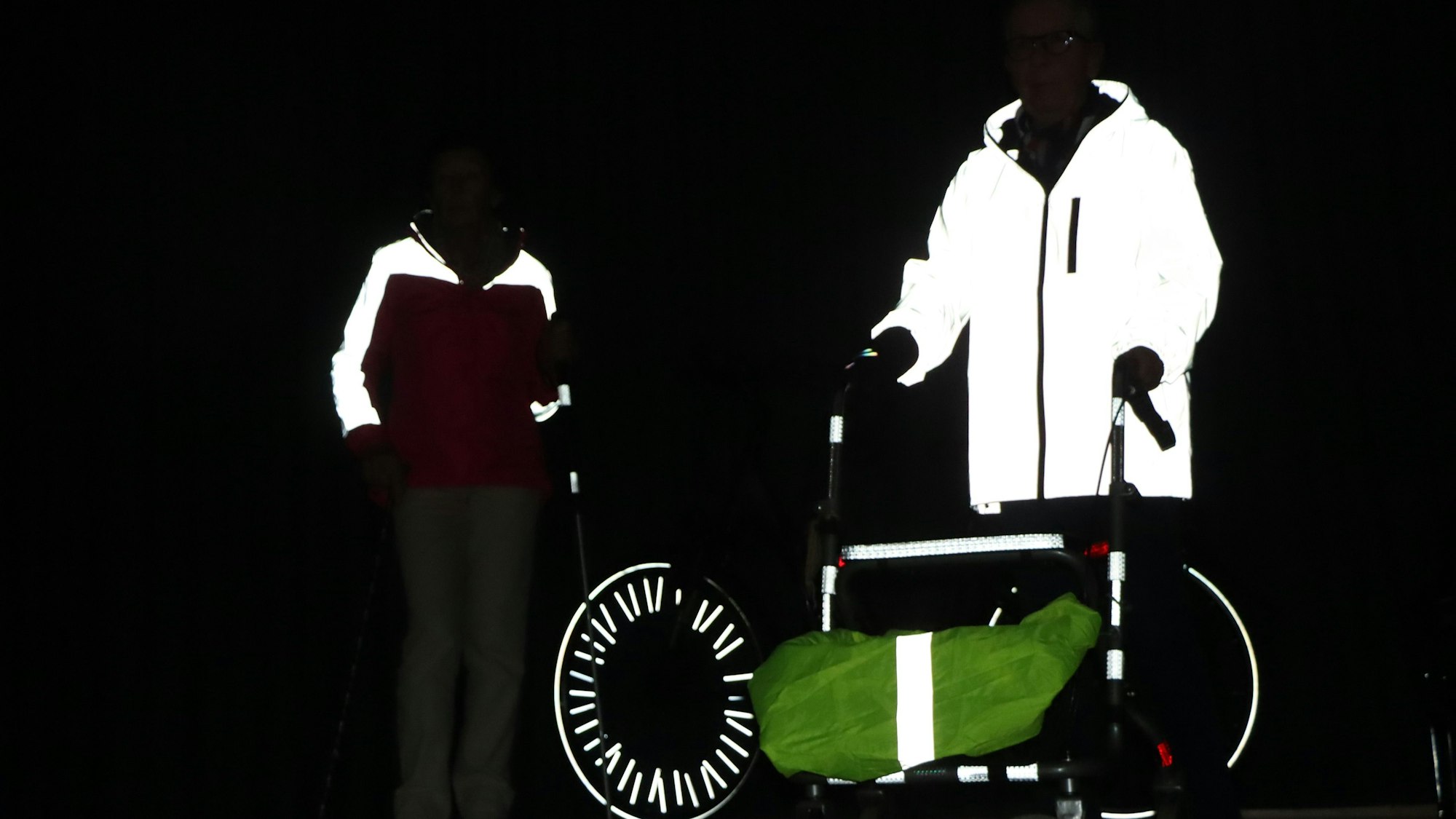 Zu sehen sind die Reflektoren und die leuchtende Bekleidung von Verkehrsteilnehmern in einer dunklen Umgebung.