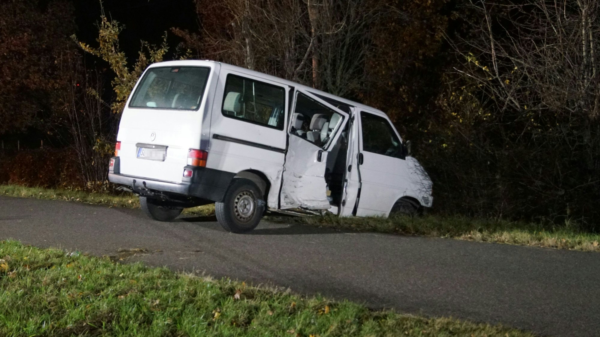 Das Bild zeigt einen weißen VW Bus, der bei der Kollision an der Beifahrerseite demoliert wurde.
