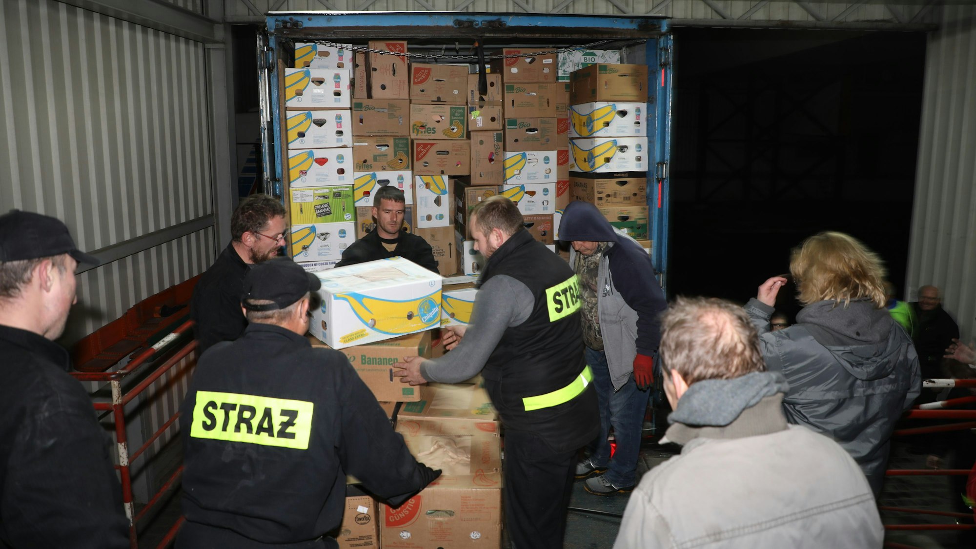 Polnische Feuerwehrleute helfen beim Abladen von Hilfsgütern aus einem 40-Tonner-Lastzug,