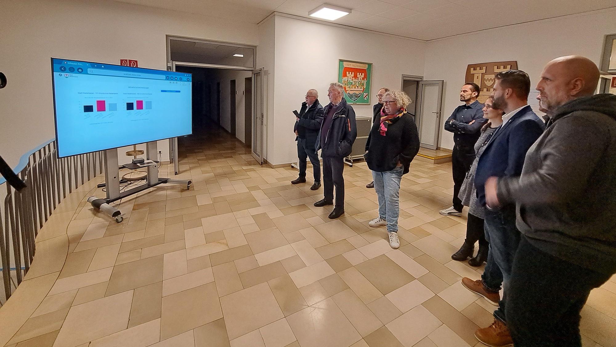 Mehrere Menschen gucken auf einen Bildschirm.