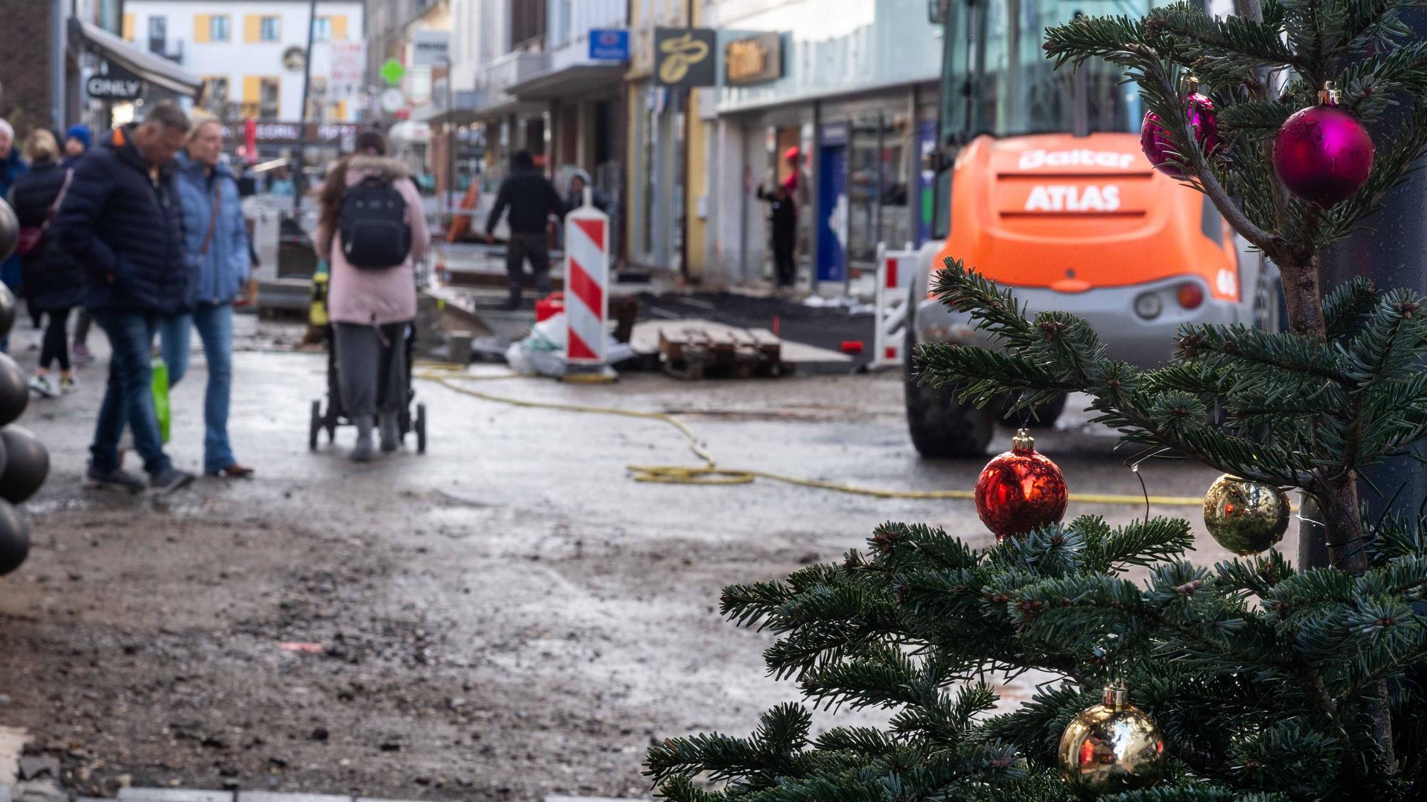 Das Bild zeigt die Euskirchener Fußgängerzone. Am rechten Bildrand ist ein Weihnachtsbaum zu sehen, im Hintergrund die Baustelle an der Neustraße.