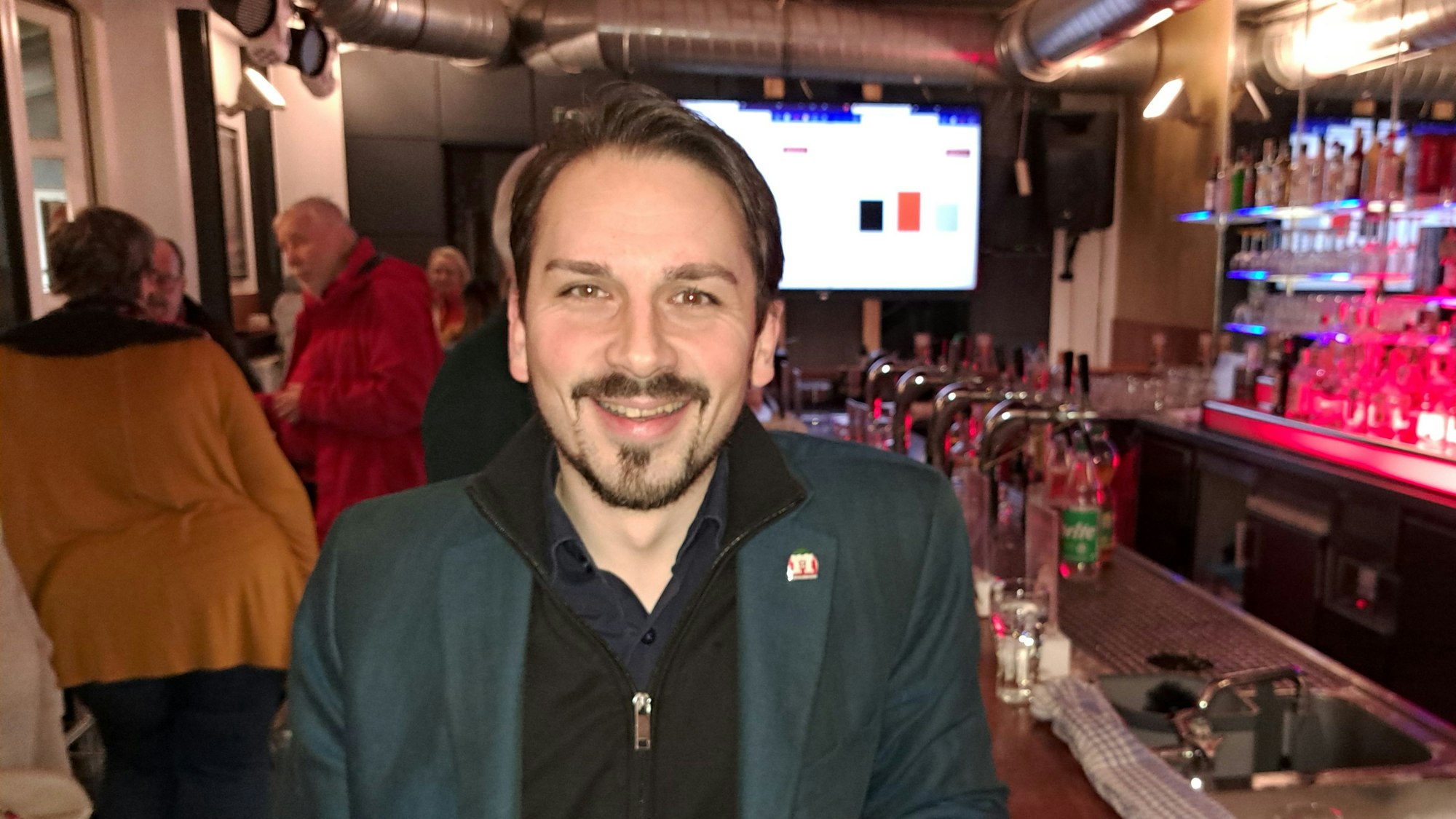 Ein Mann steht lächelnd an einer Theke.