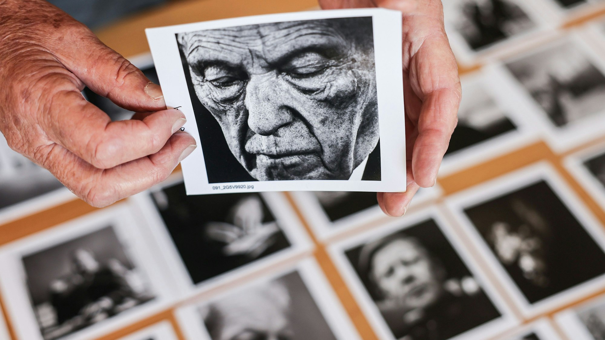 Der Porträtfotograf Konrad Rufus Müller hält in seinem Wohnzimmer einen kleinen Abzug eines Porträts von Bundeskanzler Adenauer in der Hand.