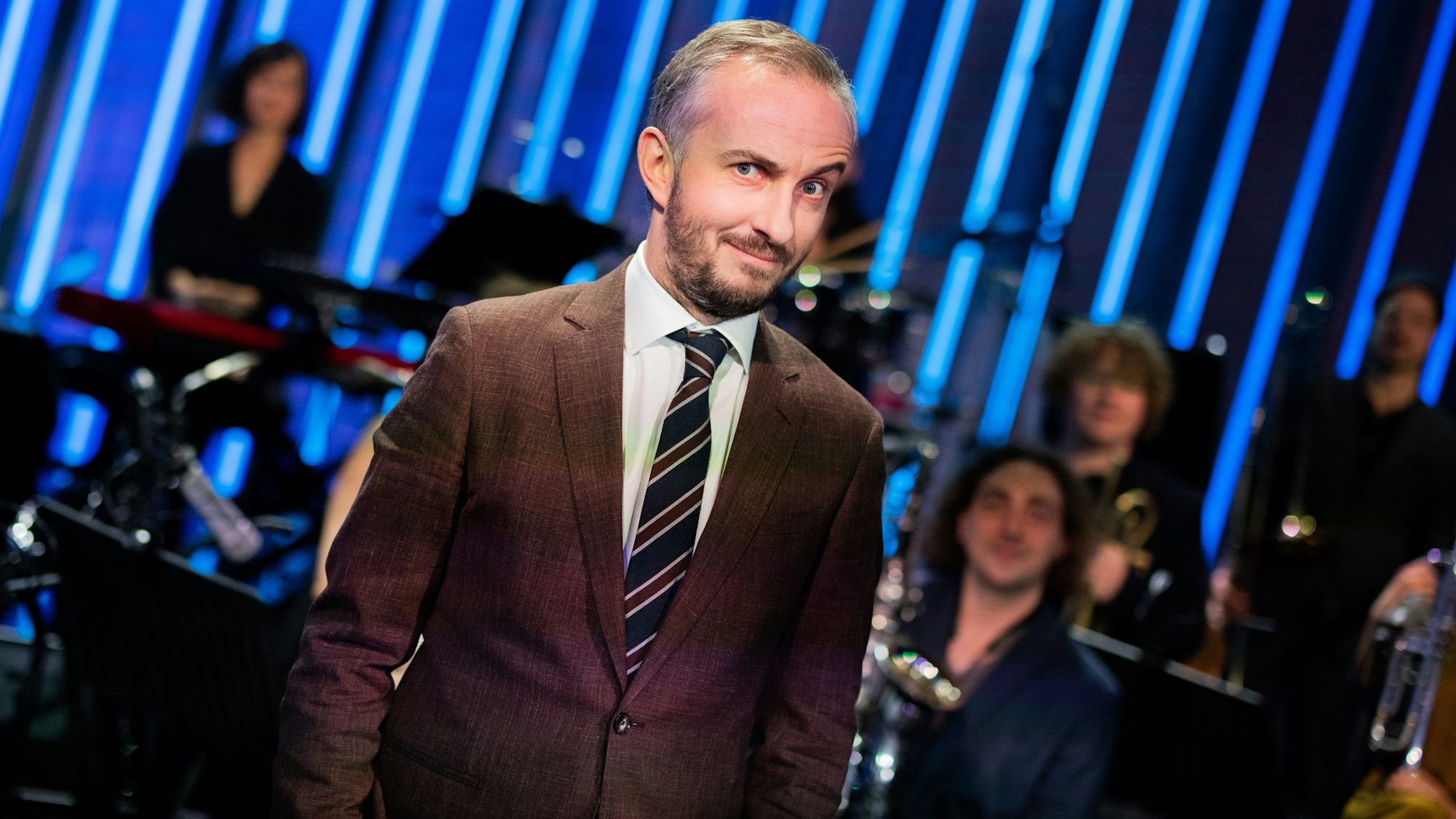 Moderator und Satiriker Jan Böhmermann steht vor Mitgliedern des Rundfunk-Tanzorchesters Ehrenfeld. 2025 gehen sie gemeinsam auf Tour. (Archivbild)