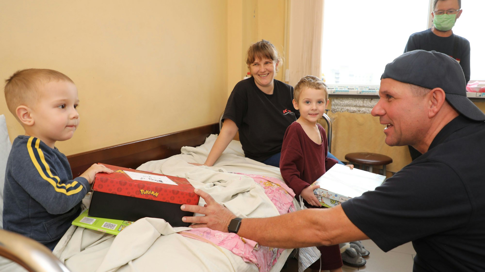 Ein Hilfskonvoifahrer gibt einem Kind in einem Krankenbett ein Geschenk.