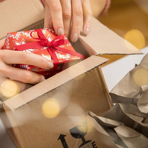 Eine Person legt ein kleines Weihnachtsgeschenk in einen Karton.