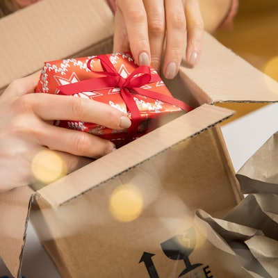 Eine Person legt ein kleines Weihnachtsgeschenk in einen Karton.