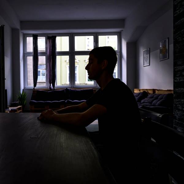 Jugendlicher an einem Küchentisch im Schatten.