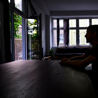 Jugendlicher an einem Küchentisch im Schatten.