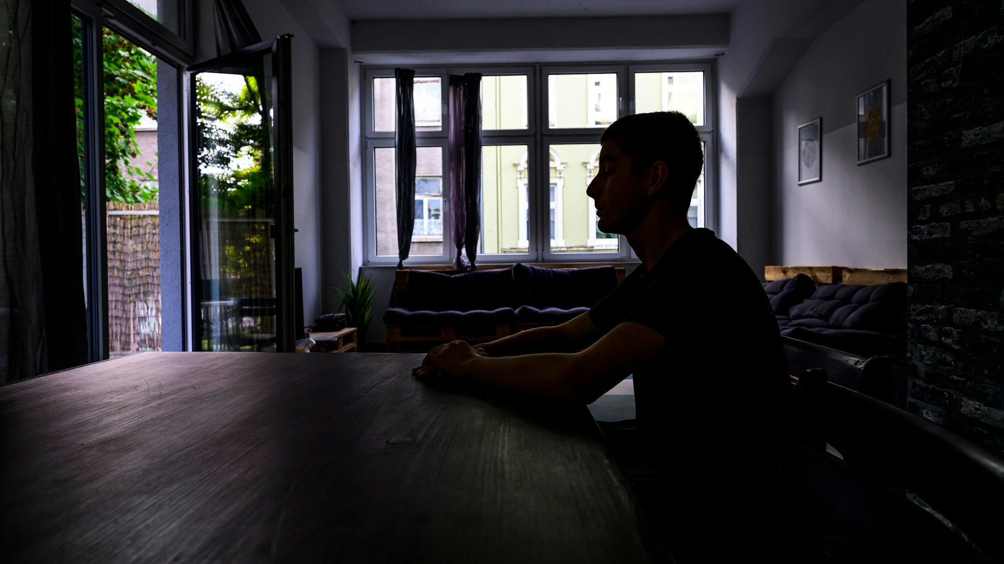 Jugendlicher an einem Küchentisch im Schatten.