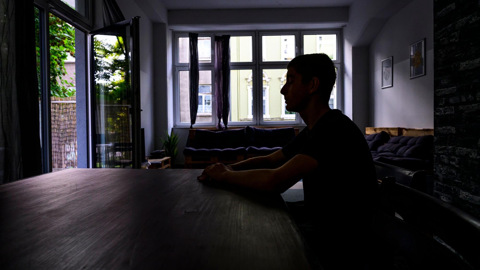 Jugendlicher an einem Küchentisch im Schatten.